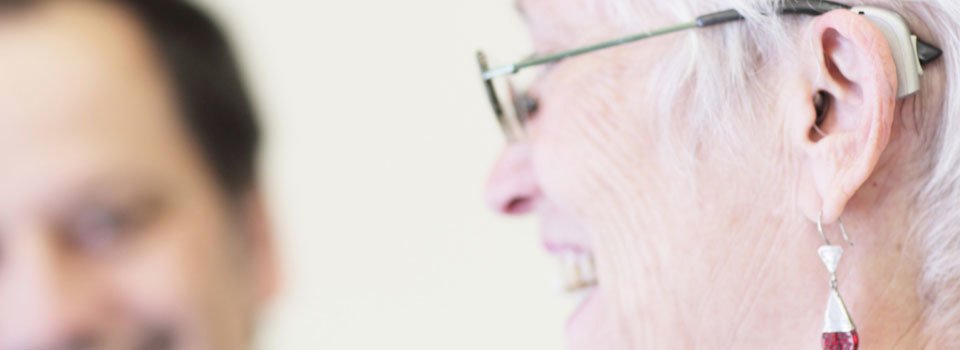 A senior woman with a hearing aid on her glasses